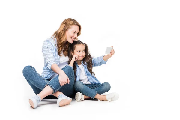 Счастливая мать и дочь делают селфи на смартфоне вместе изолированные на белом — стоковое фото