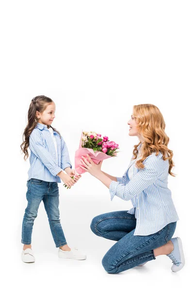 Дочка представляє букет квітів веселій мамі ізольовано на білому, концепція Дня матері — стокове фото