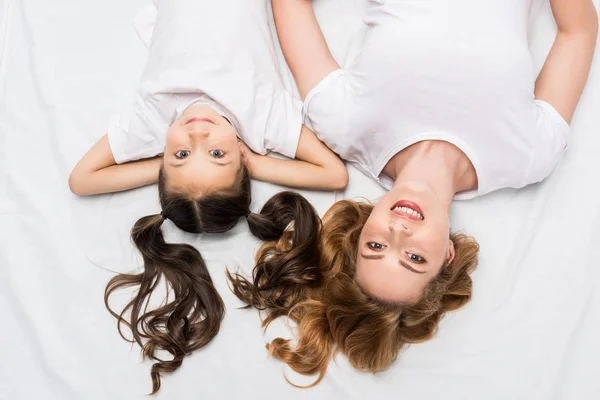 Visão aérea de mãe e filha sorridente deitada na cama — Fotografia de Stock