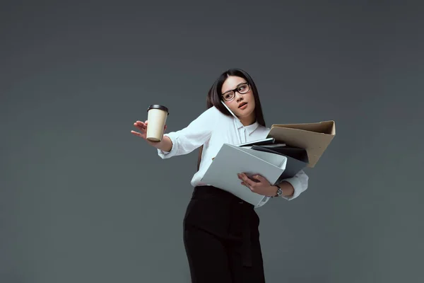 Attrayant femme d'affaires avec des dossiers et du café pour aller parler par smartphone isolé sur gris — Photo de stock