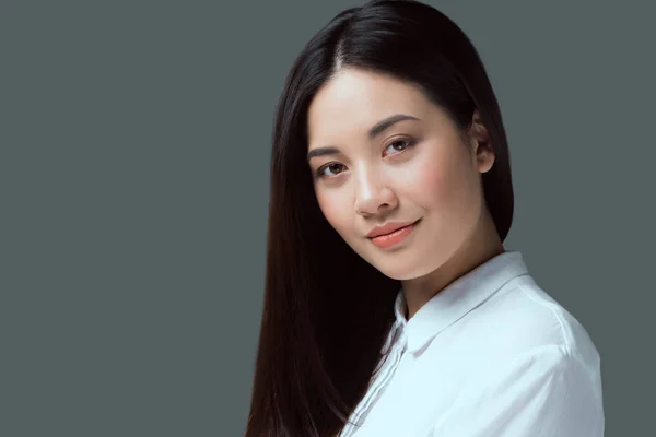 Retrato de hermosa joven asiática mujer sonriendo a cámara aislada en gris - foto de stock