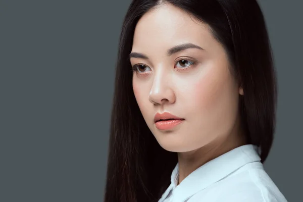 Крупным планом портрет красивой молодой азиатской женщины, смотрящей в сторону, изолированной на сером — стоковое фото