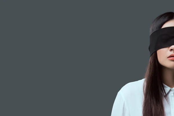 Abgeschnittene Aufnahme einer jungen Frau mit schwarzer Augenbinde isoliert auf grau — Stockfoto