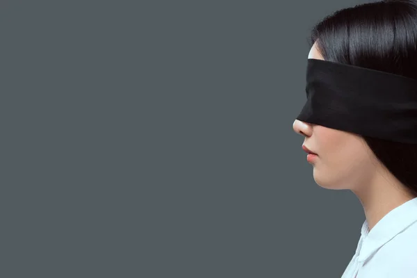 Side view of young woman wearing black blindfold isolated on grey — Stock Photo