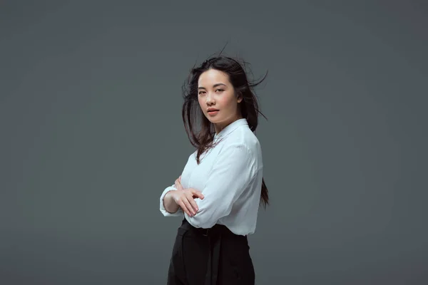 Portrait de belle fille asiatique debout avec les bras croisés et regardant caméra isolé sur gris — Photo de stock