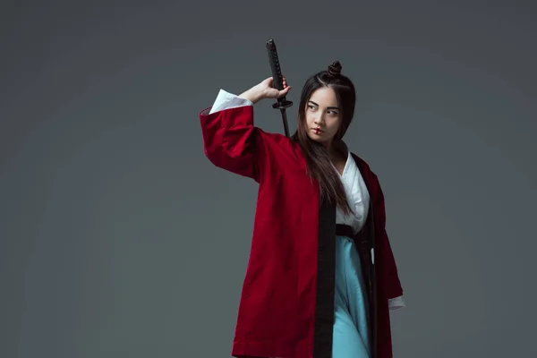 Samurai im Kimono hält Katana-Schwert in der Hand und schaut isoliert auf grau — Stockfoto