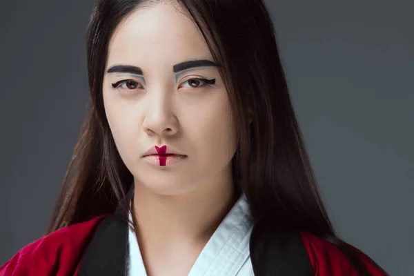 Nahaufnahme Porträt einer jungen Frau mit geschminktem Kimono und Blick in die Kamera isoliert auf grau — Stockfoto