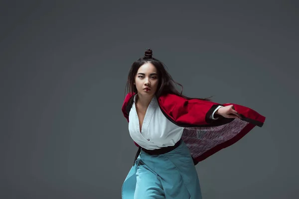 Schöne asiatische Frau in traditionellen japanischen Kimono Blick auf Kamera isoliert auf grau — Stockfoto