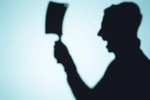 Scary shadow of screaming person holding meat knife on blue — Stock Photo