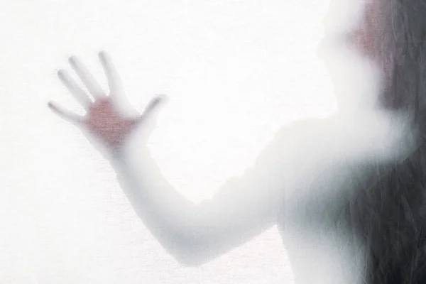 Blurry silhouette of screaming person touching frosted glass — Stock Photo