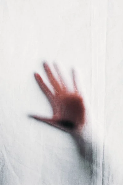 Blurry silhouette of human hand touching veil — Stock Photo