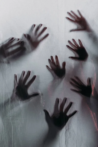 Blurry scary silhouettes of human hands touching frosted glass — Stock Photo