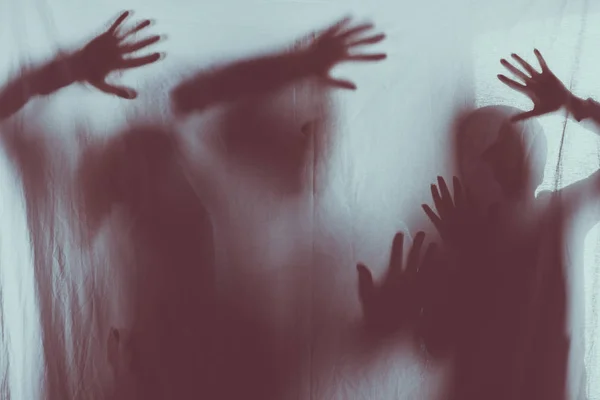 Blurry scary silhouettes of people touching frosted glass with hands — Stock Photo