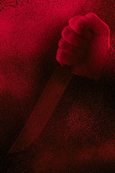 Cropped shot of human hand holding knife in red light with glitches — Stock Photo