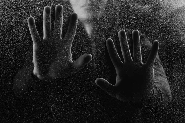 Tiro cortado de pessoa tocando vidro fosco na escuridão — Fotografia de Stock