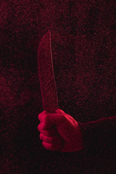 Recortado tiro de hombre sosteniendo cuchillo en luz roja - foto de stock