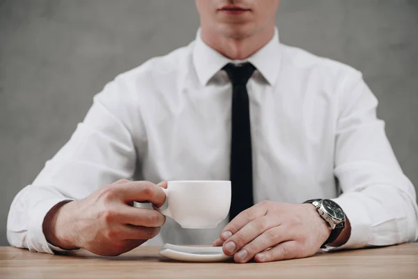 Tiro recortado de empresário segurando xícara de café em cinza — Fotografia de Stock