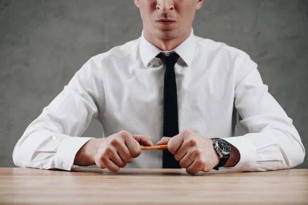 Mid section of businessman holding broken pencil in hands — Stock Photo