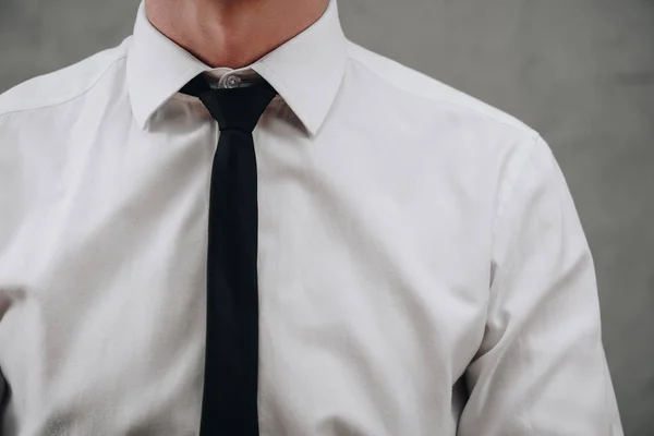 Tiro recortado de hombre de negocios en camisa blanca y corbata negra en gris - foto de stock