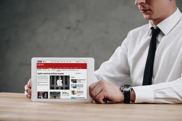 Colpo ritagliato di uomo d'affari in possesso di tablet digitale con sito web di notizie della BBC sullo schermo — Foto stock