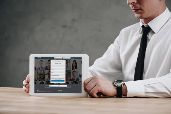 Cropped shot of businessman holding digital tablet with linkedin website on screen — Stock Photo