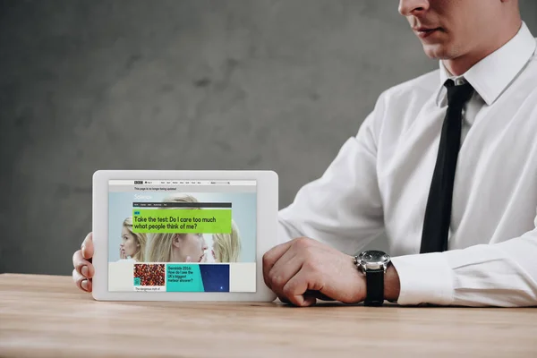 Cropped shot of businessman holding digital tablet with BBC website on screen — Stock Photo