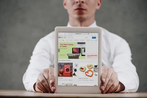 Cropped shot of man holding digital tablet with ebay website on screen — Stock Photo