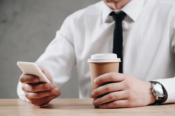 Plan recadré d'un homme d'affaires tenant une tasse en papier et utilisant un smartphone — Photo de stock