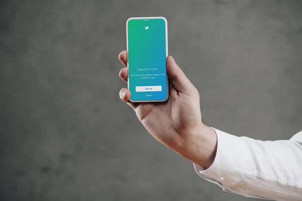 Schnappschuss von Mann, der Smartphone mit Twitter-Anwendung auf dem Bildschirm hält — Stockfoto