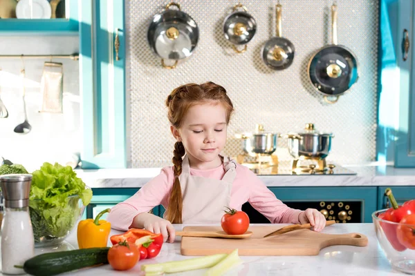 Entzückendes kleines Kind in Schürze kocht in Küche — Stockfoto