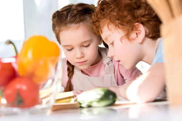 Niños enfocados leyendo el libro de cocina mientras cocinan juntos en la cocina - foto de stock