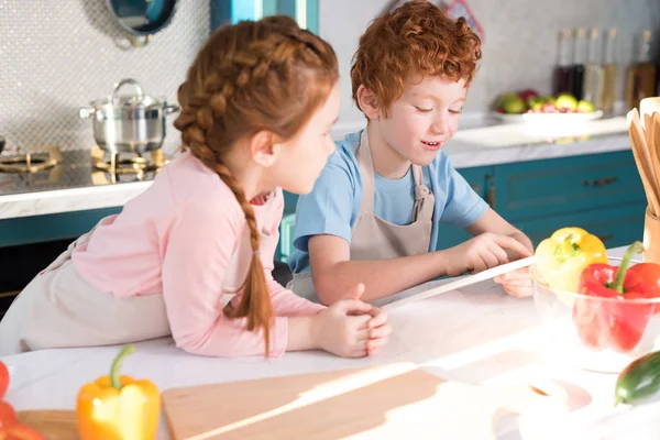 Чарівні маленькі діти використовують цифровий планшет під час приготування їжі разом на кухні — стокове фото