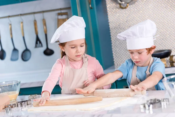 Niños pequeños y lindos preparando masa para galletas en la cocina - foto de stock