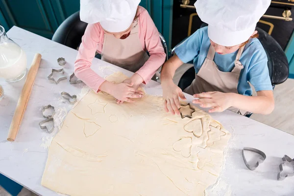 Вид зверху на дітей у кухарських капелюхах, які готують печиво разом — стокове фото