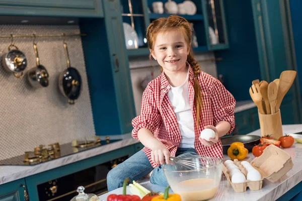 Niedliches kleines Kind, das Teig schwenkt und in der Küche in die Kamera lächelt — Stockfoto