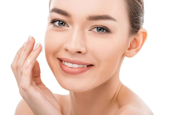 Beautiful smiling girl with clean face applying cosmetic cream, isolated on white — Stock Photo