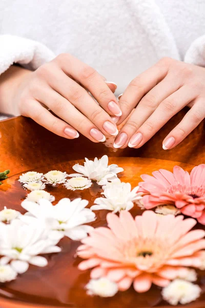 Vista ritagliata della donna che fa procedura spa con fiori, concetto di cura delle unghie — Foto stock