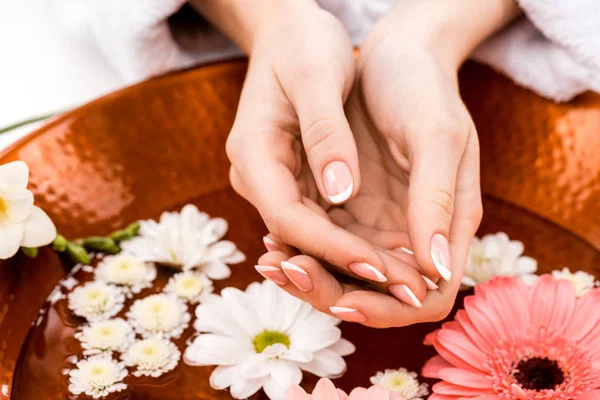 Vista recortada de la mujer haciendo procedimiento de spa con flores en el salón de belleza - foto de stock