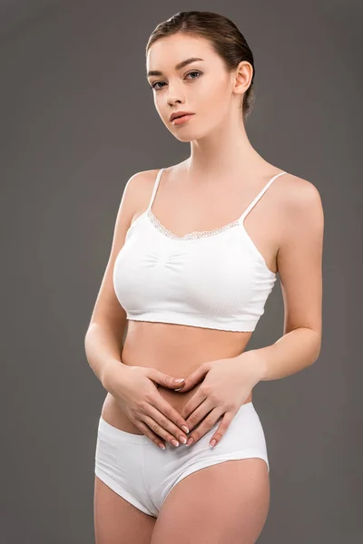 Junge Frau posiert in weißer Unterwäsche, isoliert auf grau — Stockfoto