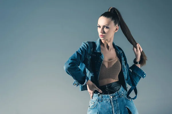 Morena joven posando en ropa de mezclilla de moda, aislado en gris - foto de stock