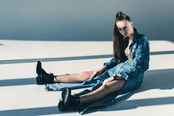 Belle jeune femme en denim vêtements assis sur le sol — Photo de stock