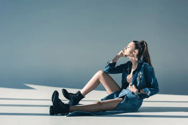 Mulher atraente em roupas jeans sentado no chão — Fotografia de Stock