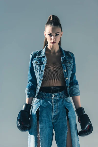 Bela menina elegante em roupas jeans com luvas de boxe, isolado em cinza — Fotografia de Stock