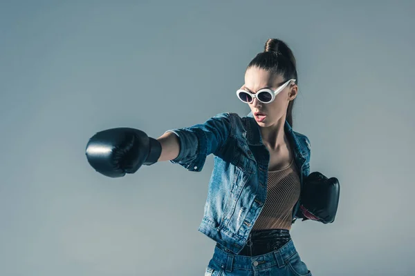 Élégant boxe fille en denim vêtements et lunettes de soleil, isolé sur gris — Photo de stock