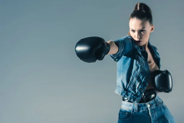 Селективный фокус боксерской девушки в джинсовой одежде, изолированной на сером — стоковое фото
