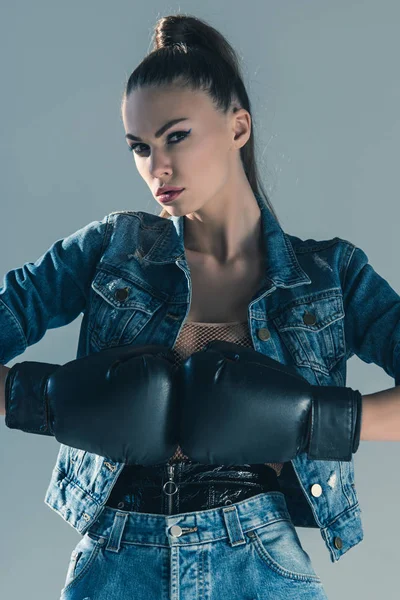 Стильна модель в джинсовому одязі і боксерських рукавичках, ізольована на сірому — стокове фото