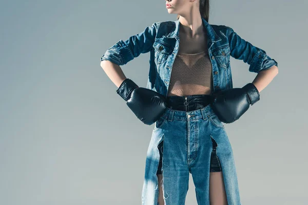 Обрезанный вид стильной девушки в джинсах и боксёрских перчатках, изолированный на сером — стоковое фото