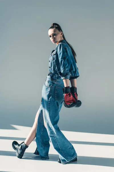 Fille élégante en vêtements en denim et gants de boxe posant pour le tournage de mode — Photo de stock