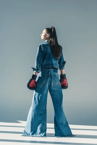 Rear view of stylish girl in denim clothes and boxing gloves — Stock Photo