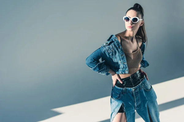Fashionable brunette model posing in denim style and sunglasses — Stock Photo